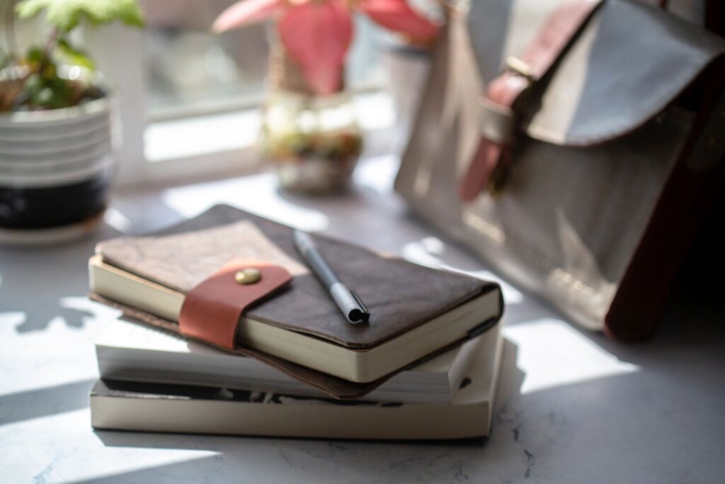 notebook and briefcase on table beside window